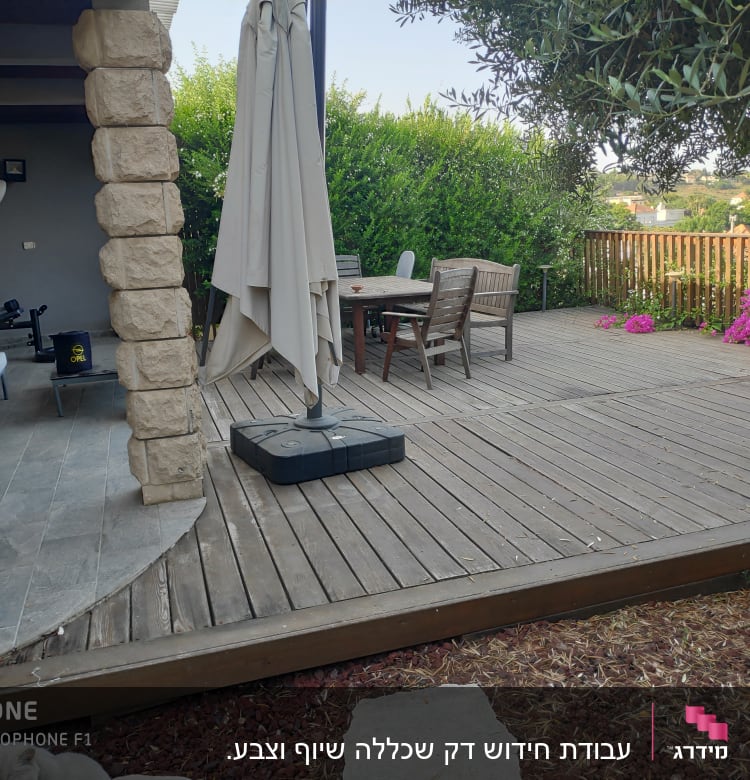 דק עץ עם שולחן וכיסאות בגינה